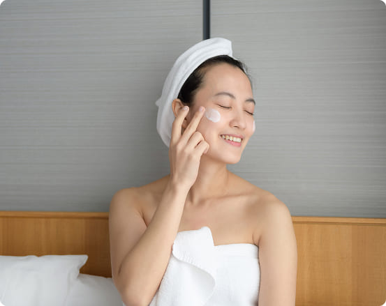 happy young asian woman applying face lotions